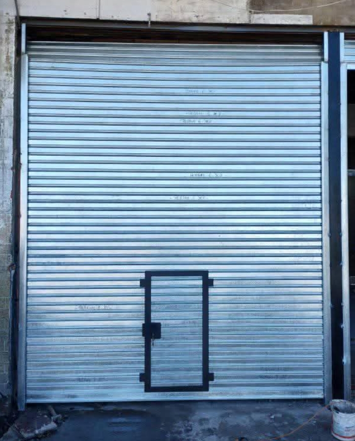 alt="Cortina metálica galvanizada enrollable con cerradura central — destrabado, cambio de ejes y resortes, motorización en Olivos"