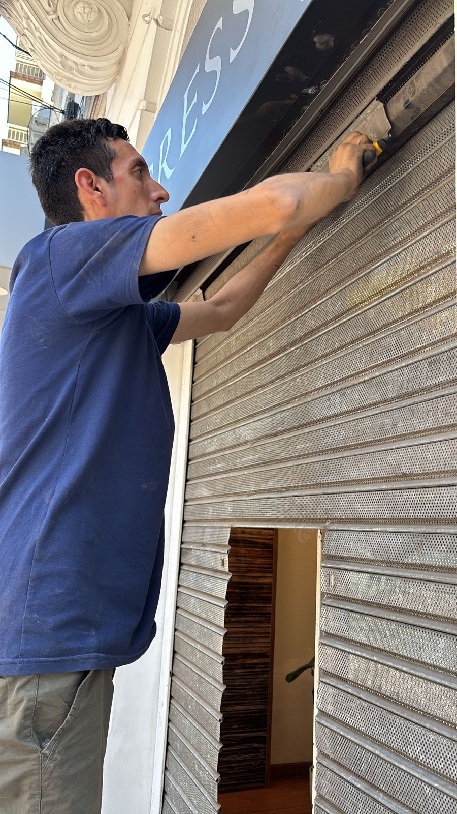 "Técnico realizando reparación de cortina metálica comercial con ajuste del paño y sistema de cierre"