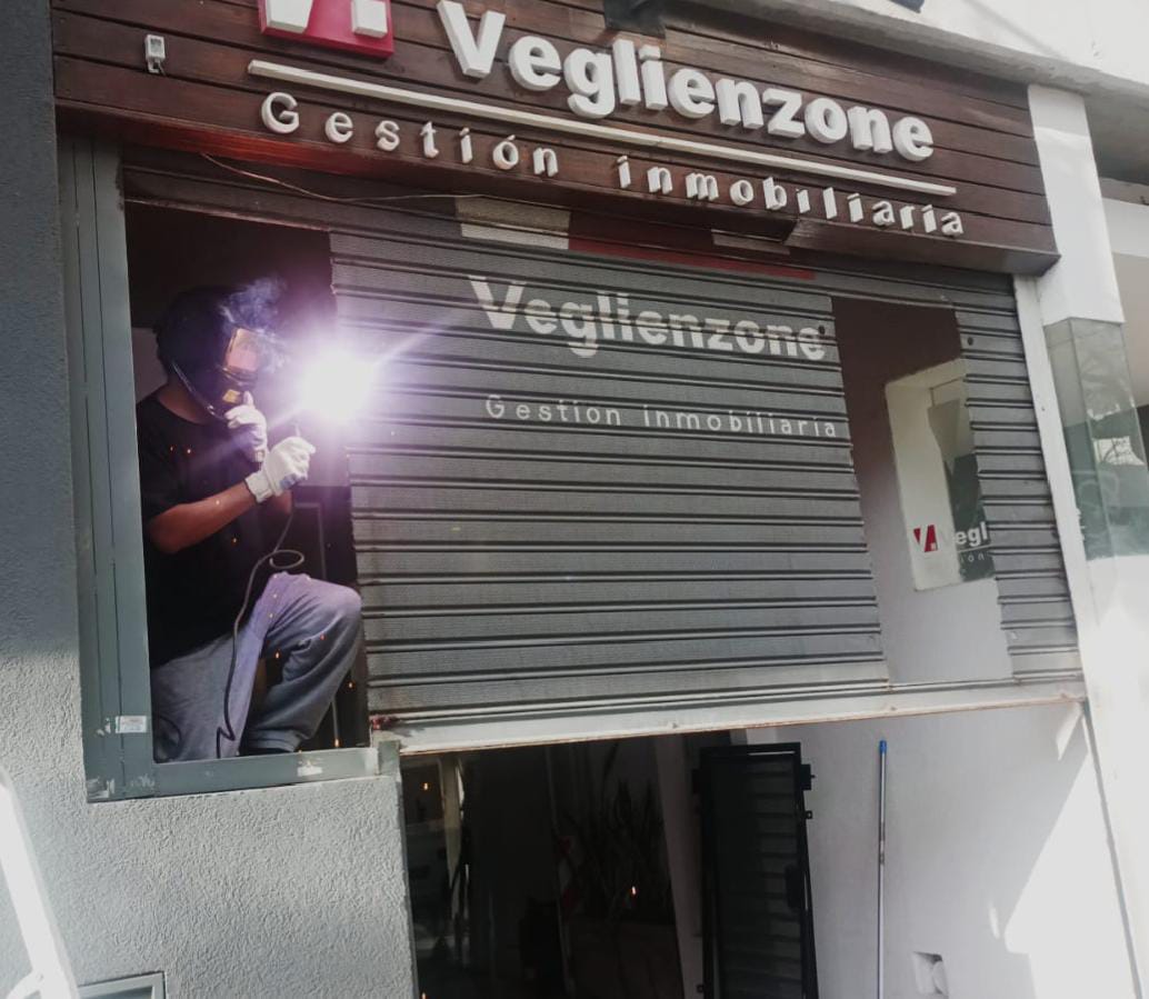 Técnico reparando cortina metálica atascada en local comercial de CABA